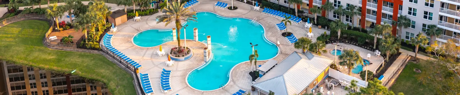Vista aérea da área da piscina do resort com palmeiras e espreguiçadeiras azuis