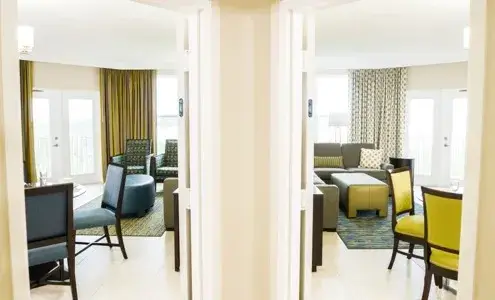 View through connecting doorway showing two separate living areas with seating and dining