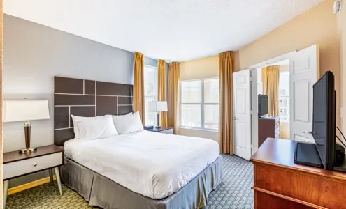 Queen bedroom with upholstered headboard, nightstands, and flat-screen TV