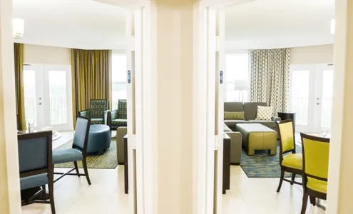 View through connecting doorway showing two separate living areas with seating and dining